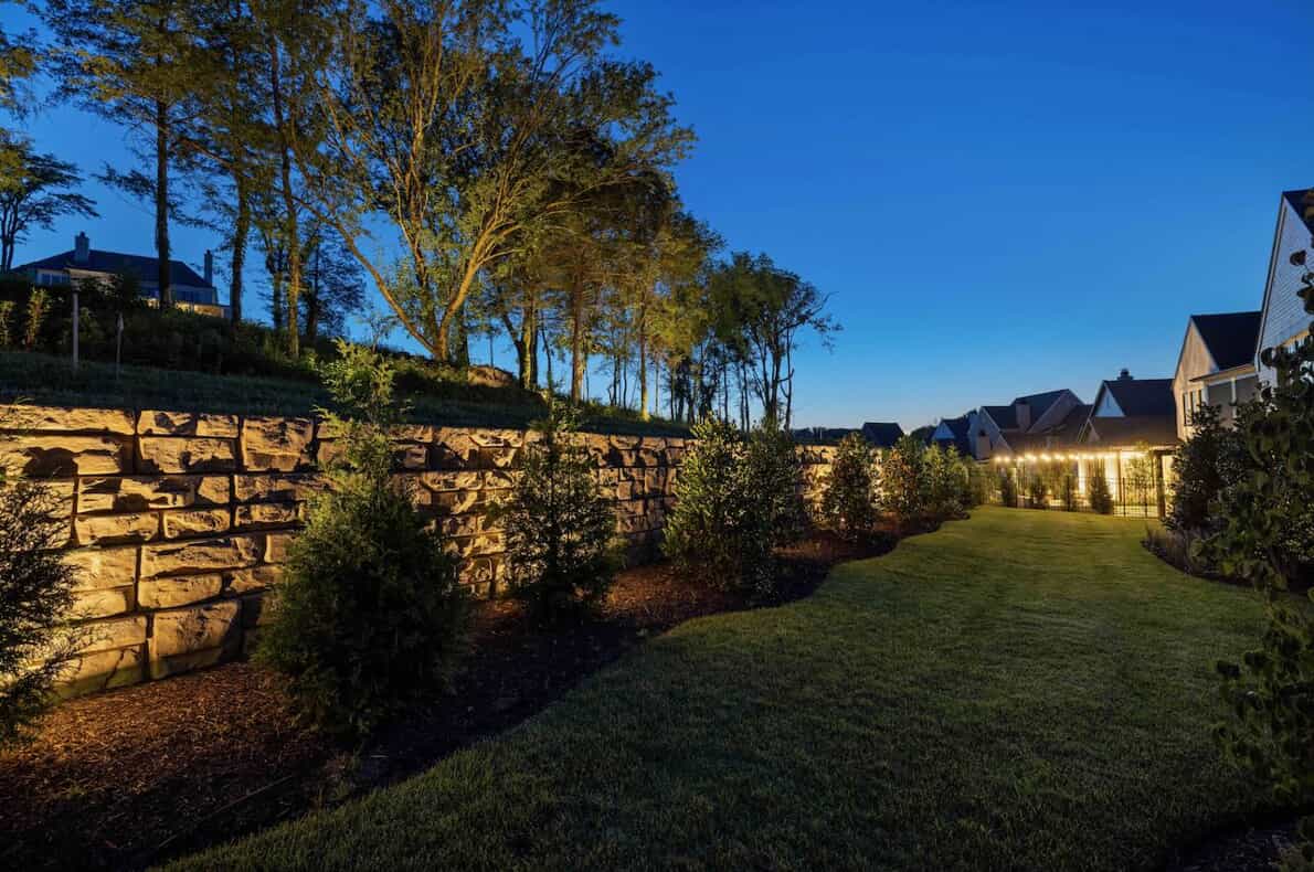 A picturesque stone wall set against beautifully lit landscaped greenery