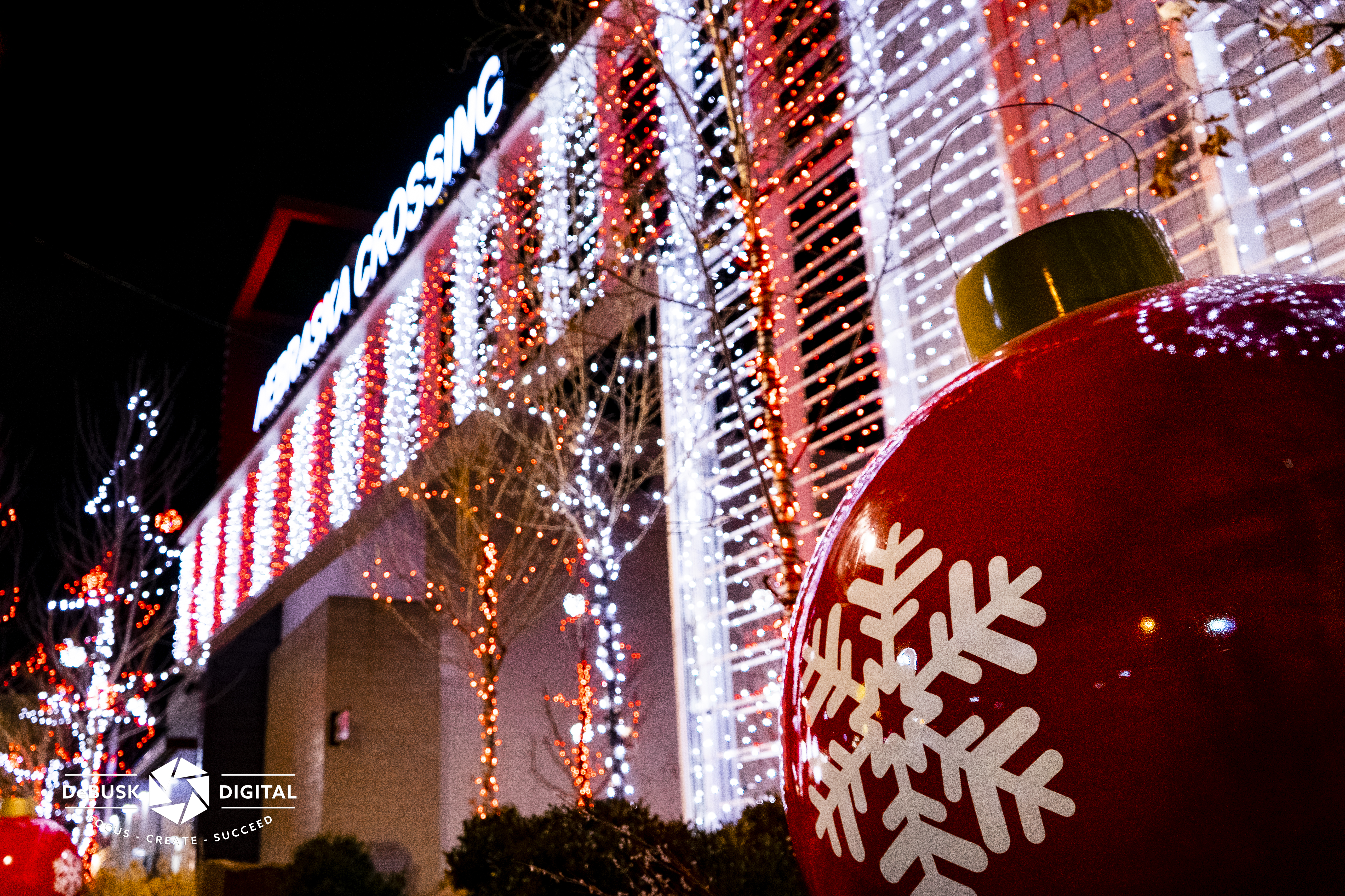 Holiday lights on outdoor mall building plus in trees
