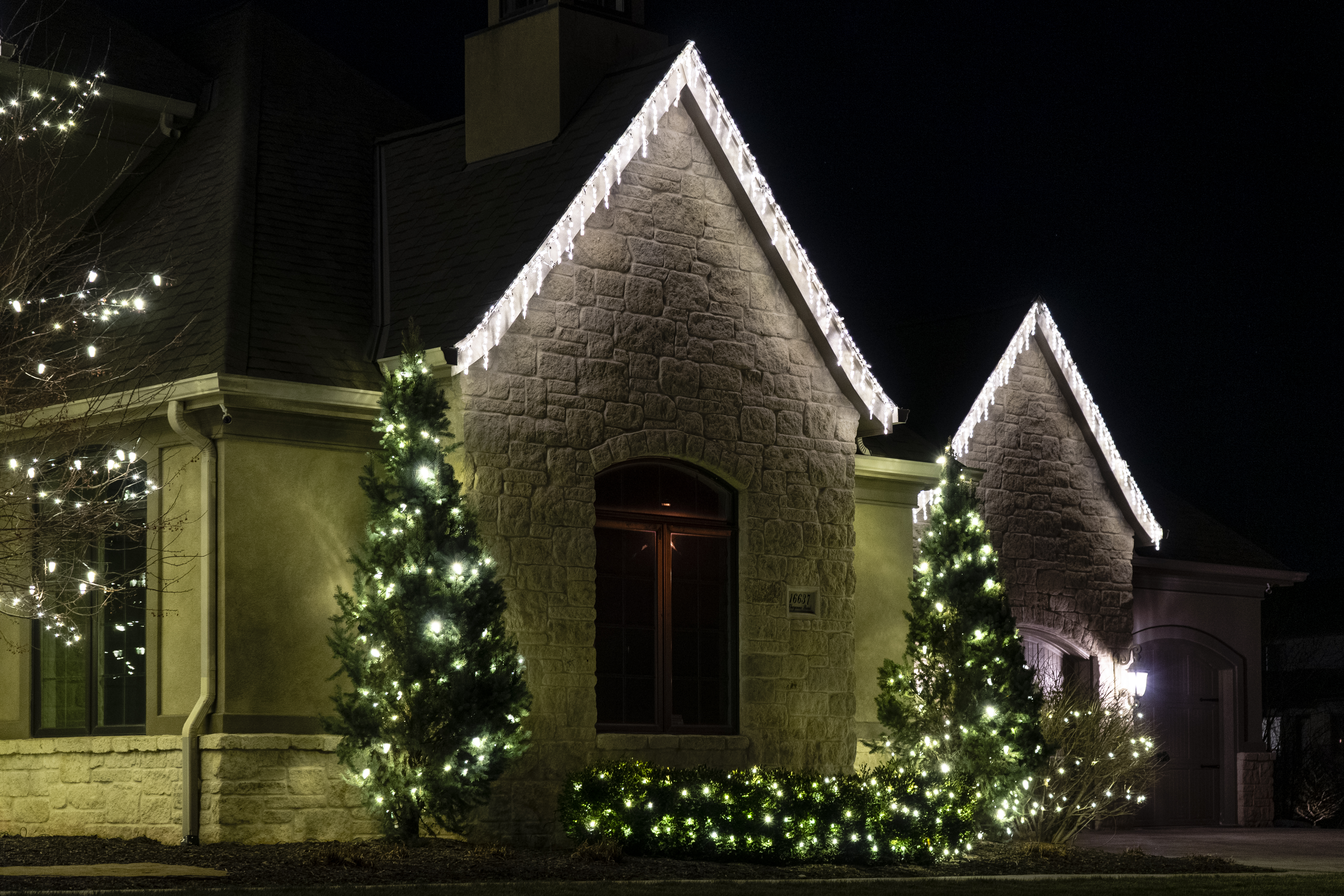 Residential House with Holiday Lighting on roof and trees.