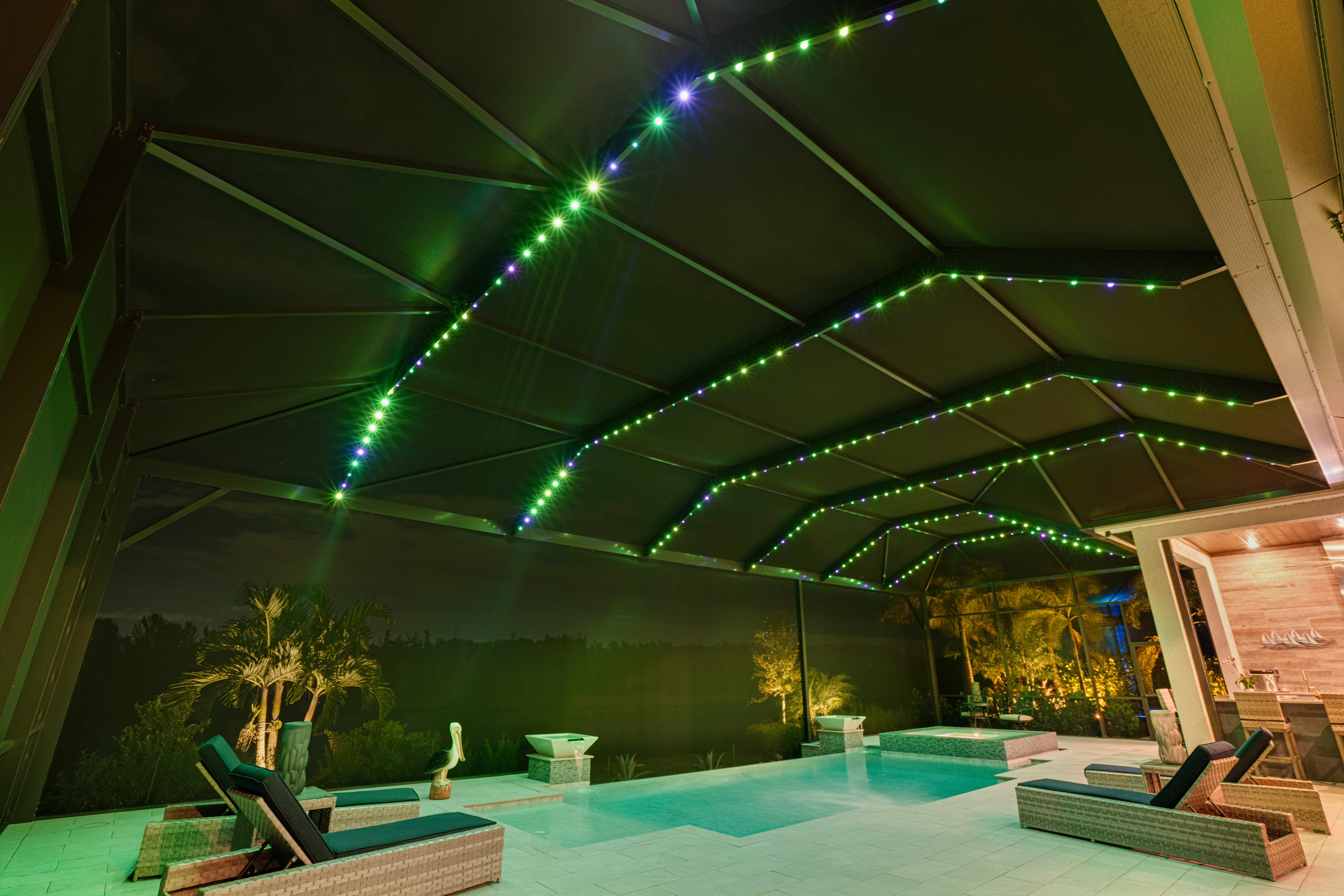 Permanent Halloween lighting displaying the Bubbling Swamp green and purple pattern on a Fort Myers pool cage