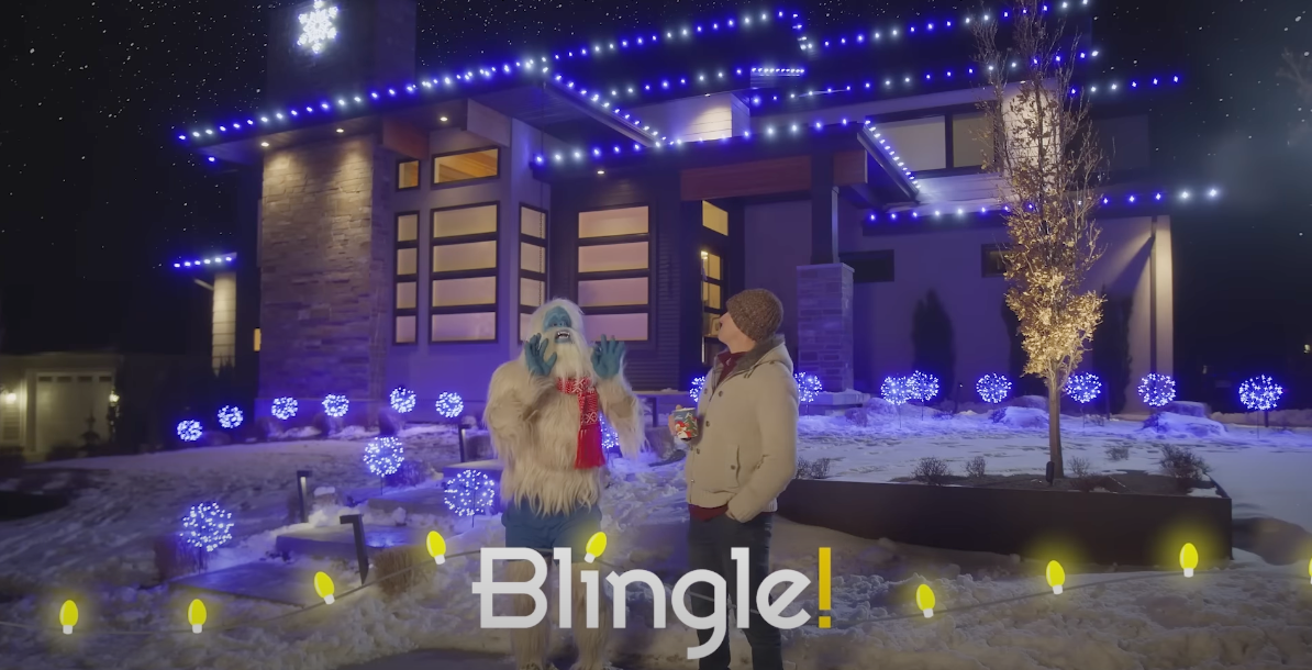 yeti and a man outside a house with christmas lights